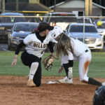 Two softball players in action at a base; one is sliding in, while the other prepares to tag her out.