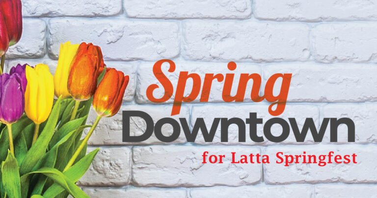 Orange tulips in a vase beside text reading "Spring Downtown for Latta S." on a white brick background.
