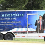 A trailer with a ministry advertisement, showing a man speaking into a microphone and text about spreading the message to the world.