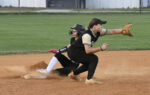 Two softball players in action, one sliding onto the base while the other attempts to make a play on the infield.