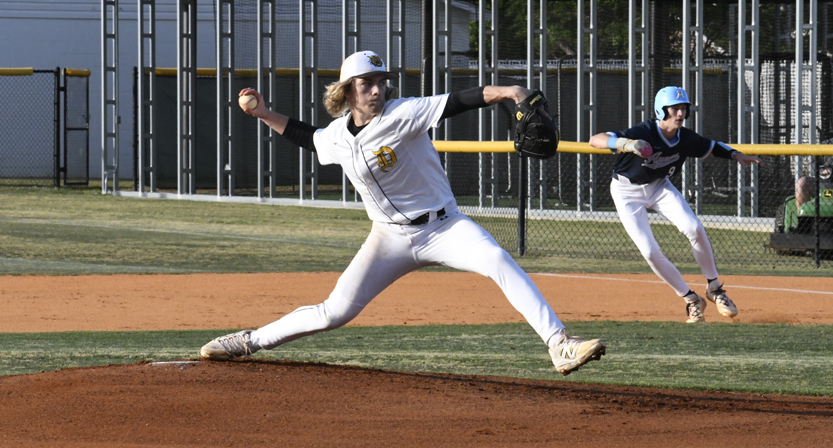 A baseball pitcher throws from the mound while a baserunner prepares to steal in the background on a sunny day.