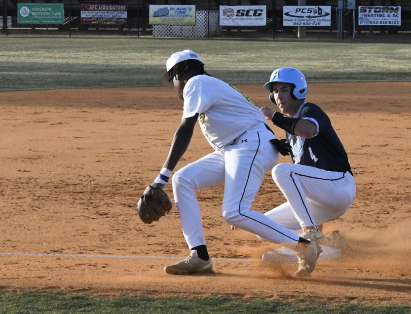 A baseball player in white attempts to tag out a sliding opponent in blue at a base during a game.