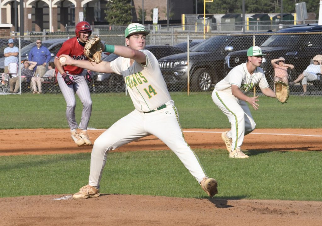 A baseball pitcher prepares to throw the ball, with a runner leading off base and an infielder ready in the background.