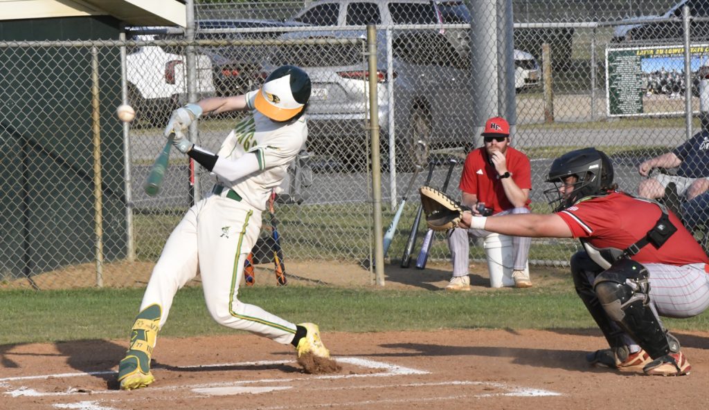 A baseball player in white uniform swings at a pitch, with a catcher and a coach in red uniforms behind home plate.