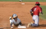 A baseball player in white slides into a base as an opponent in red attempts a tag on a dusty infield.