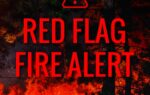 A forest fire with bold red text overlay reading “Red Flag Fire Alert” and a warning symbol, issued by the Forestry Commission.