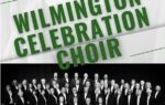 A large choir dressed in formal black attire stands together on stage under a sign reading "Wilmington Celebration Choir."