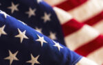 Close-up of the United States flag showing white stars on a blue field and red and white stripes in the background.