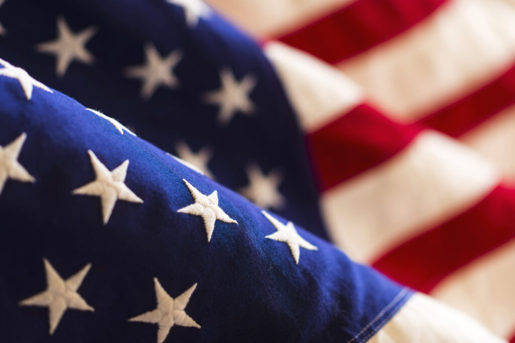 Close-up of the United States flag showing white stars on a blue field and red and white stripes in the background.