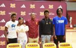 Five young adults stand together in a gym, smiling, with "Marion Swamp Foxes" and school logos on a maroon backdrop.