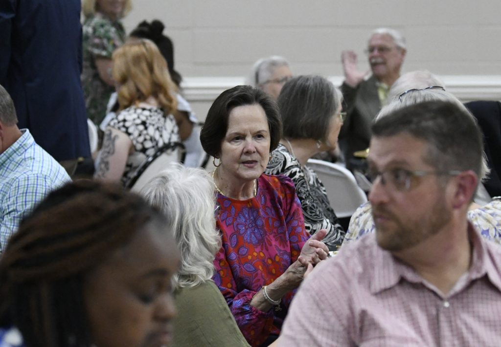 A group of people seated indoors, engaged in conversation during what appears to be a social or community event.