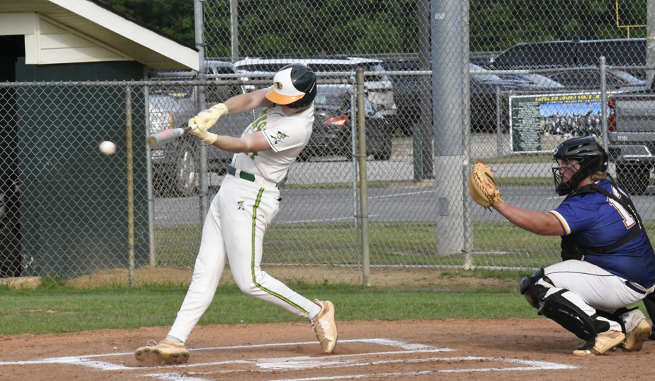Baseball player in white uniform hits a pitched ball, while the catcher in blue gear crouches behind home plate on a sunny day.