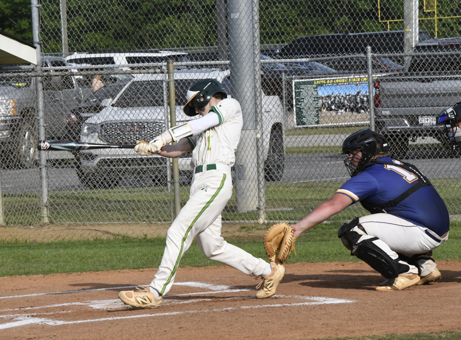 A baseball player in white swings at a pitch while a catcher in blue crouches behind home plate during a game.
