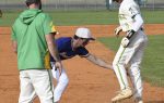 A baseball player in white leaps onto a base as a player in blue attempts to tag him, with a coach in green watching nearby.