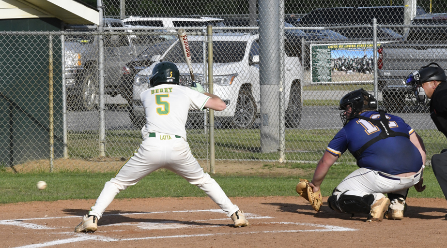 A baseball player at bat prepares to swing as the pitcher throws, with a catcher and umpire positioned behind home plate.