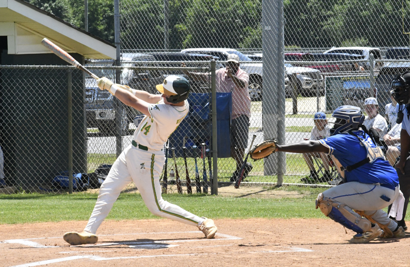A baseball player in a white uniform swings at a pitch while the catcher in blue crouches behind him during a sunny outdoor game.