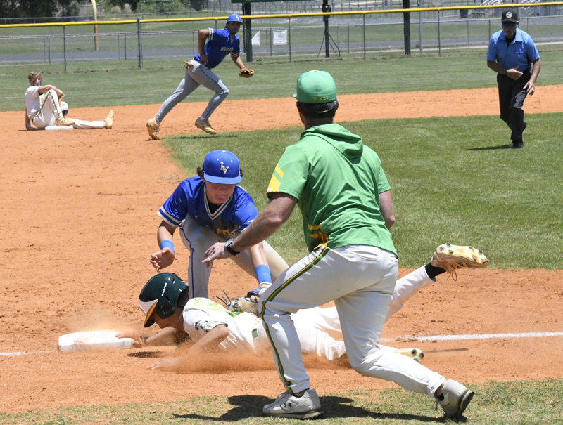 Baseball player slides into base as fielder attempts a tag, with other players and an umpire observing on a sunny field.