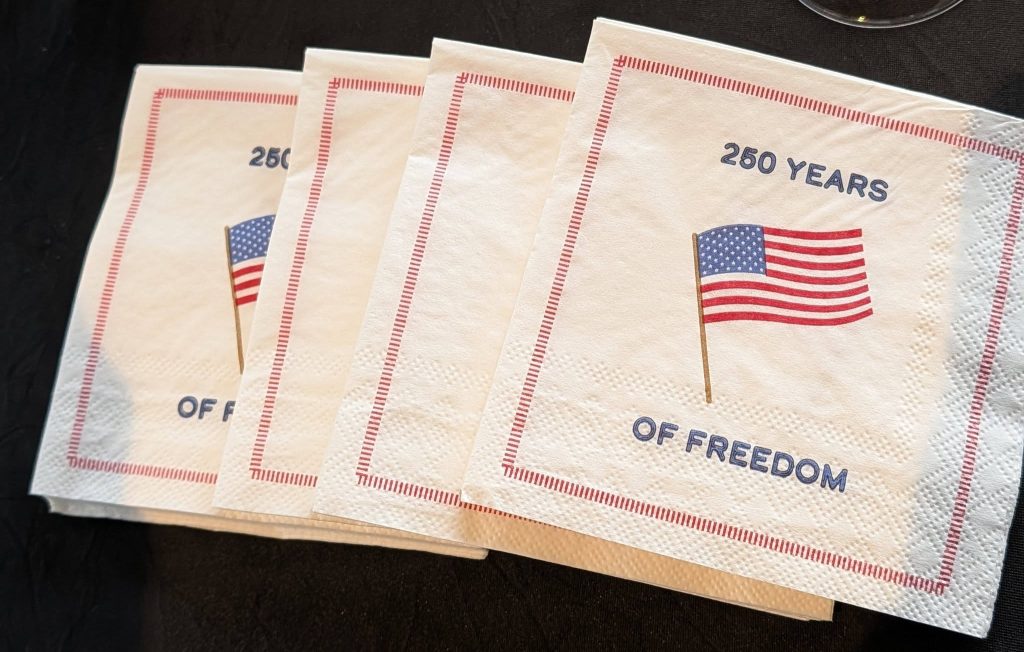 Four white napkins with a printed American flag and the text "250 years of freedom" surrounded by a red border.