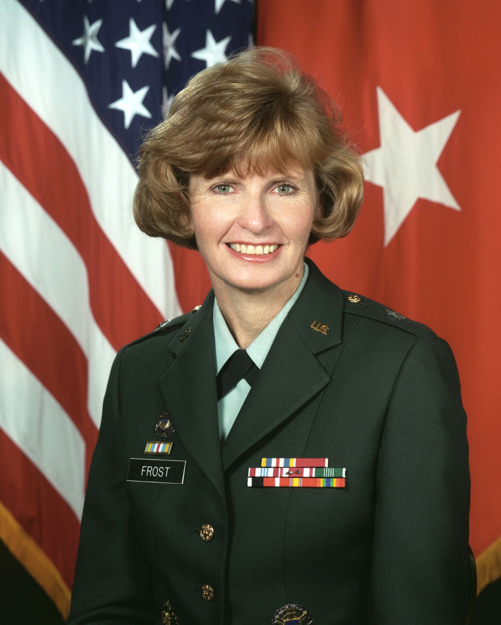 A woman in a military uniform with the name "Frost," standing in front of American and red flags with white star symbols.