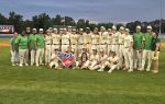 A high school baseball team poses together on a field, holding a state championship sign, with coaches in green shirts standing beside them.