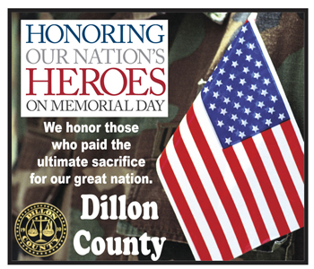 American flag held by a person in camouflage, text honors Memorial Day and fallen heroes, includes Dillon County seal and message honoring ultimate sacrifice.