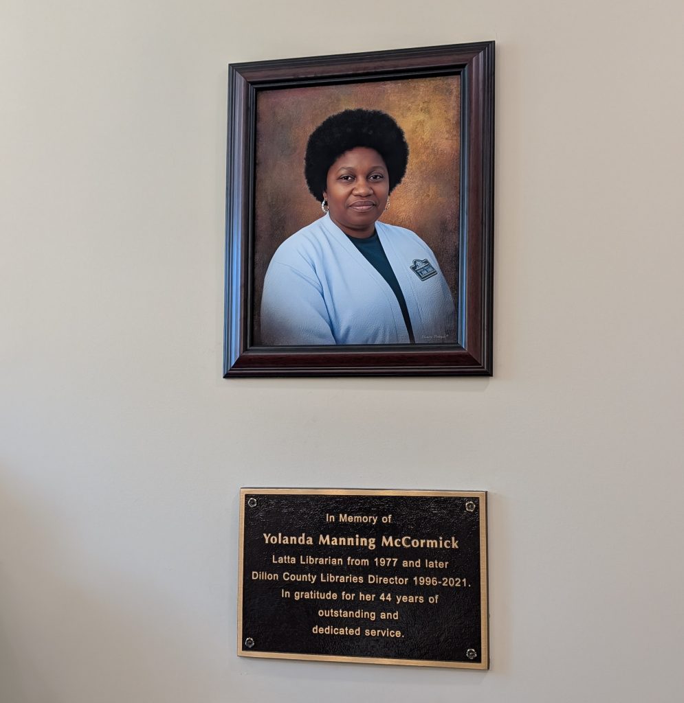 Framed portrait of a woman above a memorial plaque honoring Yolanda Manning McCormick for 44 years of dedicated library service.