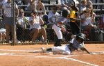 A young baseball player slides into home plate as spectators and teammates watch and cheer from the stands.