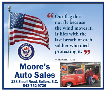 American flag waving, patriotic quote about fallen soldiers, Moore's Auto Sales logo, address, phone number, and photo of a red truck with people outside a dealership.
