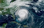 A large hurricane swirling over the Atlantic Ocean, approaching the southeastern coast of the United States, as seen from a satellite view.