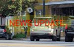 Police officer stands near vehicles and yellow caution tape outside a building, with large "NEWS UPDATE" text overlayed on the image.