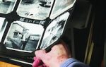 A hand holding open a photo album with black and white photographs, displaying images of people and houses.