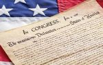 The Declaration of Independence document on top of a partial view of the United States flag.