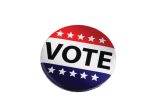 A round button with "VOTE" in bold letters, decorated with red, white, and blue stripes and white stars.