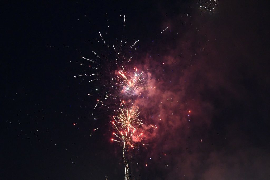 Colorful fireworks exploding in the night sky, with bright sparks and smoke trails illuminating the darkness.