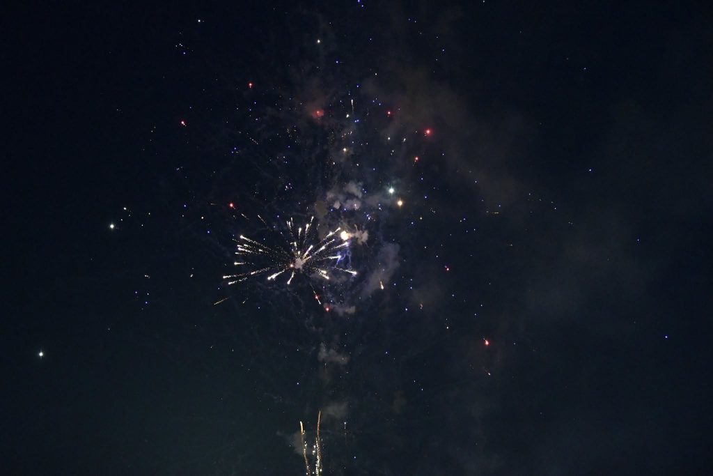 Fireworks exploding in the night sky with colorful sparks and small bursts of light scattered throughout the dark background.