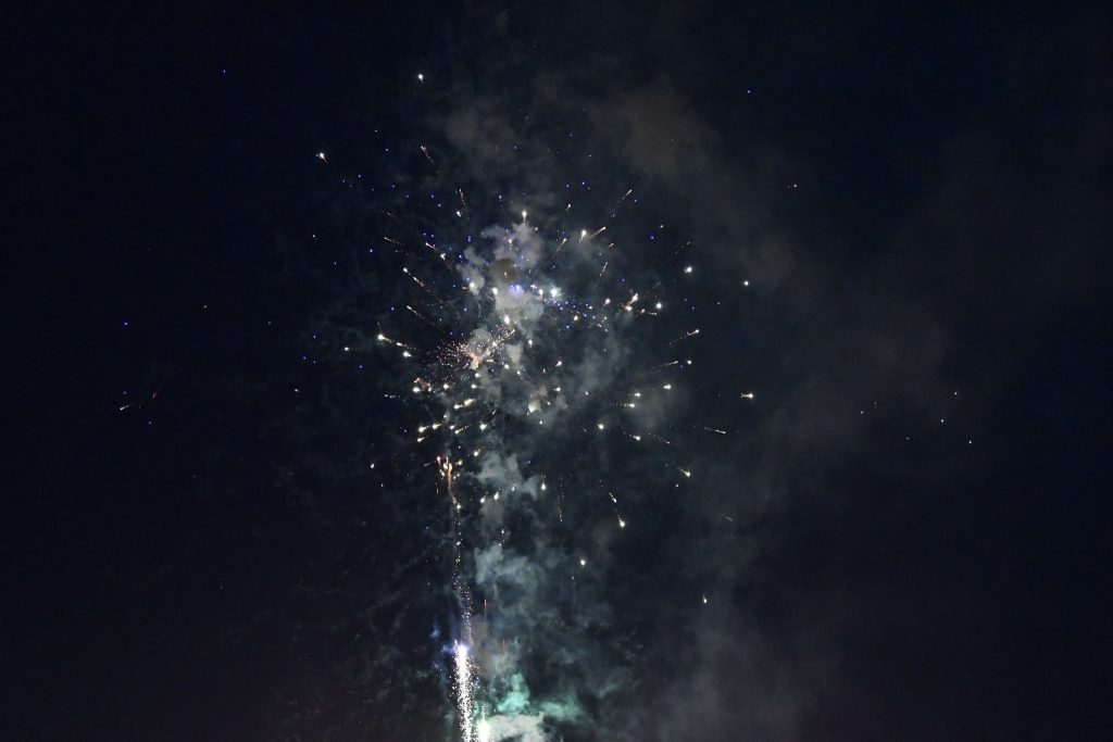 Bright fireworks exploding in the night sky, surrounded by smoke and sparks.