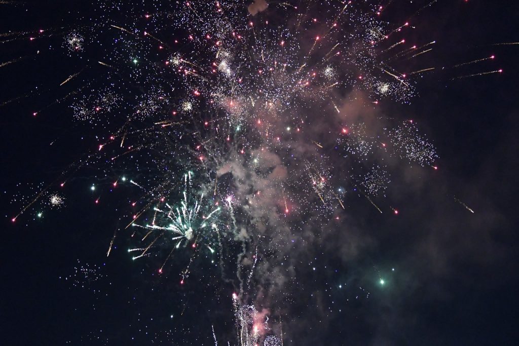 Colorful fireworks exploding across a dark night sky, with bright sparks and smoke creating a festive atmosphere.