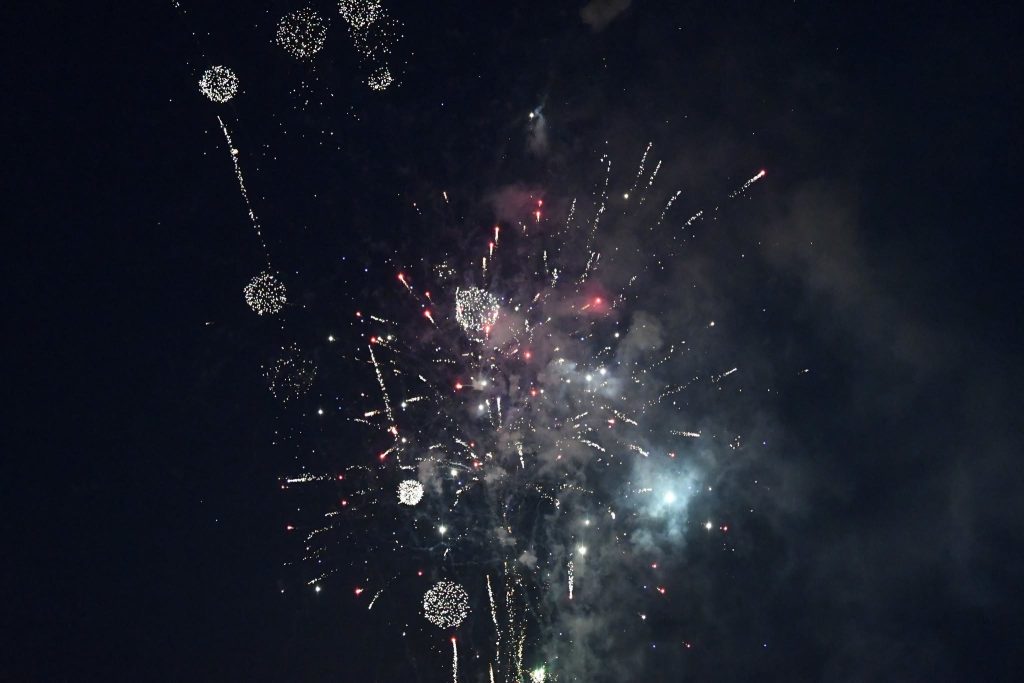 Colorful fireworks exploding in the night sky, with sparks and smoke spreading out in various directions against a dark background.