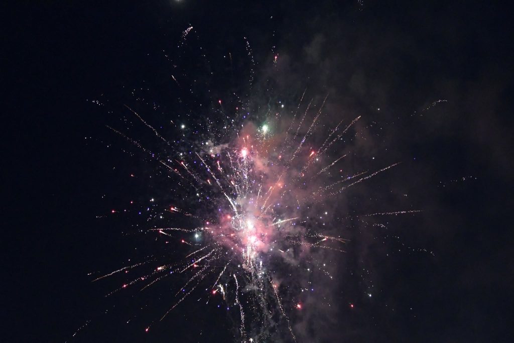 Colorful fireworks exploding in the night sky, creating bright bursts of light and smoke against a dark background.