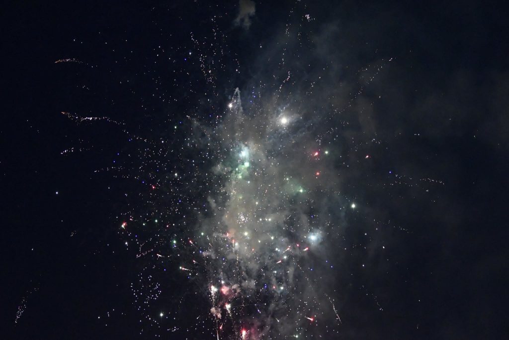 Bright fireworks exploding in the night sky, creating colorful sparks and smoke against a dark background.