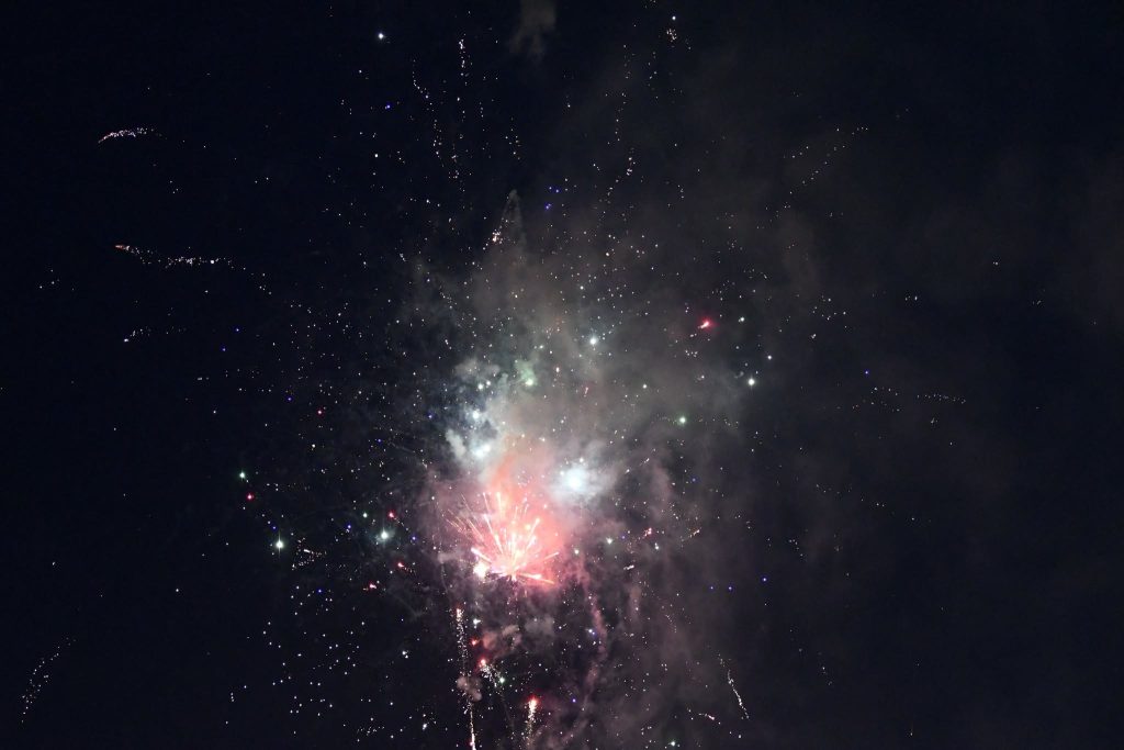 Bright fireworks exploding in the night sky, creating colorful sparks and smoke against a dark background.