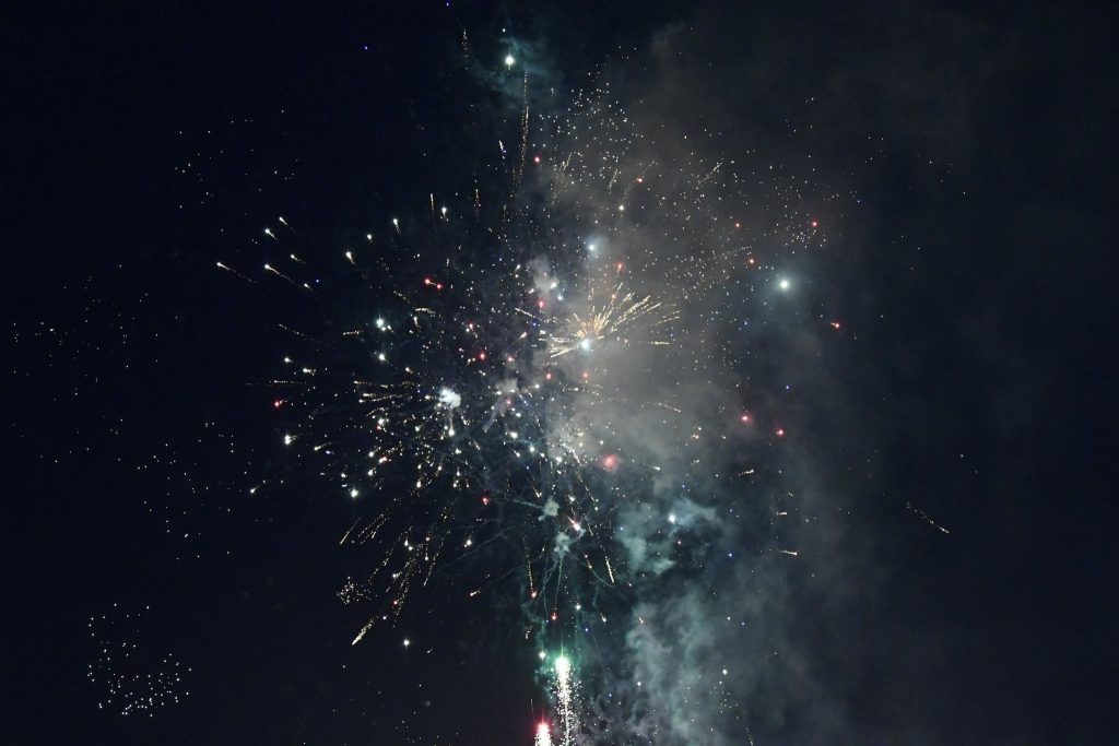 Colorful fireworks exploding against a dark night sky, with sparks, smoke, and light illuminating the scene in celebration.