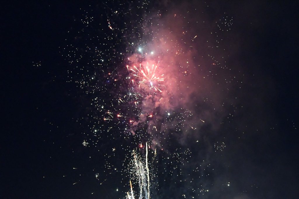 Colorful fireworks burst in the night sky, with bright sparks and smoke creating a festive, celebratory atmosphere.