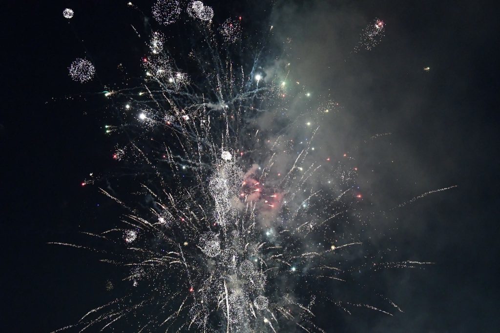 Bright fireworks exploding in the night sky, with colorful sparks and smoke illuminating the darkness.