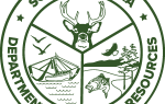 Green circular South Carolina Department of Natural Resources logo featuring a deer head, boat, fish, bird, and trees inside divided sections.